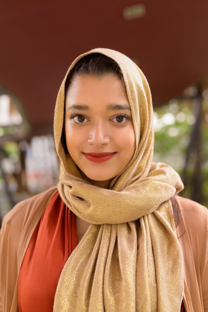 Face of young beautiful Indian Muslim woman in the city with nature